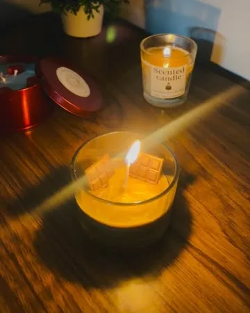 Lit amber candle glowing on a wooden table