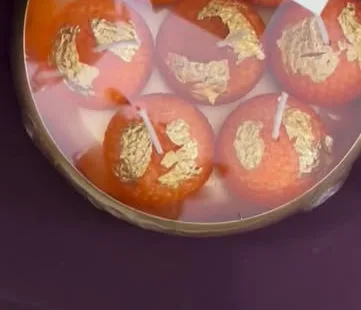 Tray of orange laddoo candles with gold leaf