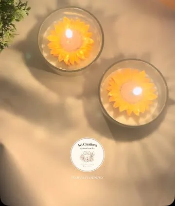 Two sunflower soy candles in glass tumblers, lit, from above